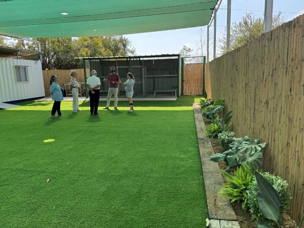 People gathered around looking at the new wide fenced green lawn at Kibbutz Urim