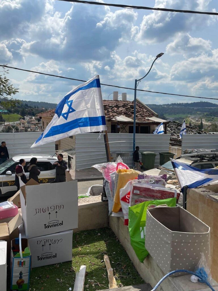 A zip-tied Israeli flag outside a leveled house